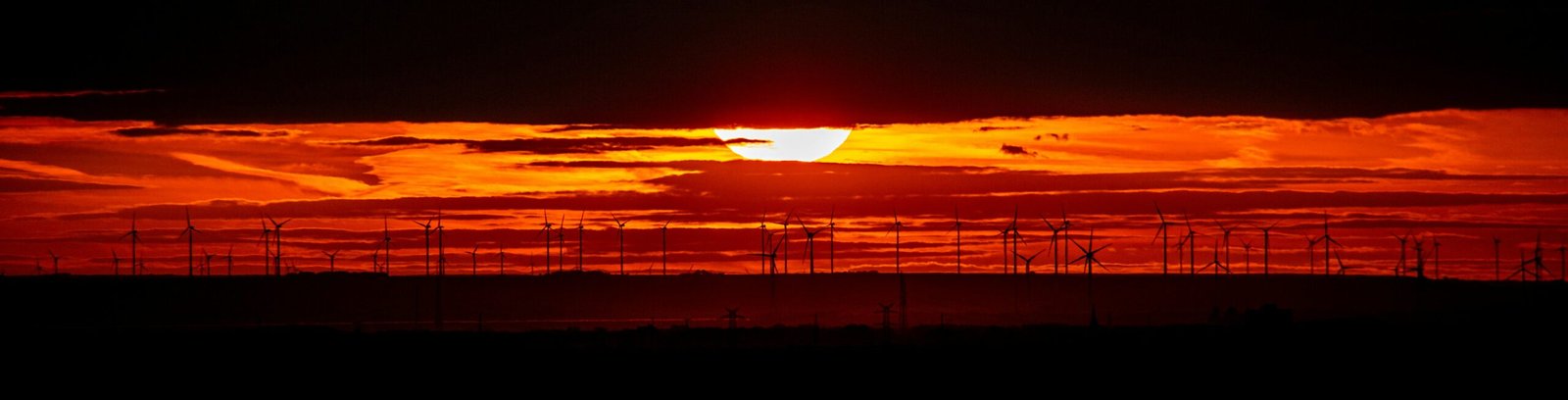 The sun is setting over the horizon of the ocean